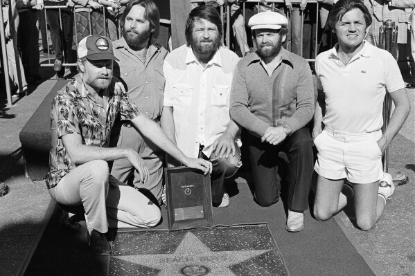 Members of The Beach Boys, from left, Mike Love, Carl Wilson, Brian Wilson, Al Jardine and Bruce Johnston, pose with their star on the Hollywood Walk of Fame, during a ceremony in Los Angeles on Dec. 30, 1980. (AP Photo/Lennox McLendon, File)