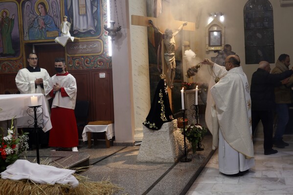 FILE -Fr. Gabriel Romanelli, Latin parish priest of Gaza Strip, left, prays during the midnight Christmas Eve mass at Deir Al Latin Holy Family Catholic Church in Gaza City, Dec. 24, 2021. (AP Photo/Adel Hana, File)