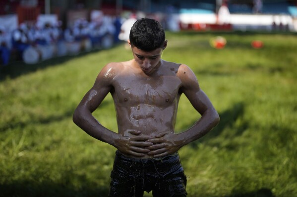 A young wrestler is doused in oil during the 664th annual Historic Kirkpinar Oil Wrestling championship, in Edirne, northwestern Turkey, Sunday, July 6, 2025.(AP Photo/Khalil Hamra)