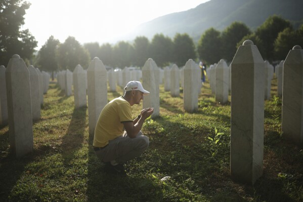 A man mourns next to the grave of his relative, a victim of the Srebrenica genocide, at the Memorial Center in Potocari, Bosnia, Friday, July 11, 2025. (AP Photo/Armin Durgut)