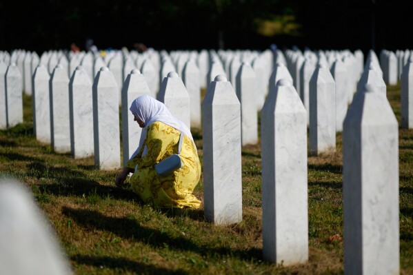 A woman mourns next to the grave of her relative, victim of the Srebrenica genocide, at the Memorial Center in Potocari, Bosnia, Friday, July 11, 2025. (AP Photo/Darko Bandic)