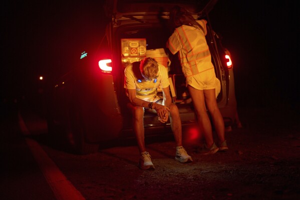 Danny Westergaard rests beside Jennifer Drain, his cousin and crew lead, during the second night of the Badwater 135 Ultramarathon, Tuesday, July 8, 2025, in Death Valley National Park, Calif. (AP Photo/John Locher)