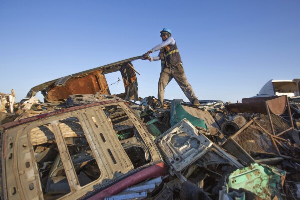 A man rearranges scrap metal at a collection site in Harare, Zimbabwe, Sunday, June 8, 2025. (AP Photo/Aaron Ufumeli)