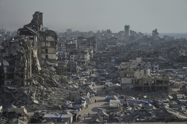 Tents sheltering displaced Palestinians are seen amid war-damaged infrastructure in Gaza City, Thursday, July 17, 2025. (AP Photo/Jehad Alshrafi)