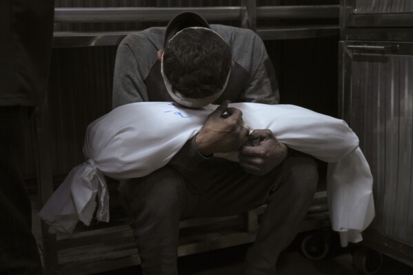 Hossam Azzam holds the body of his child, Amir, who was killed in an Israeli military airstrike on Gaza, at Shifa Hospital in Gaza City Tuesday, July 15, 2025. (AP Photo/Jehad Alshrafi)