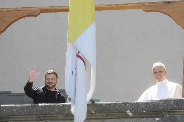 Ukraine President Volodymyr Zelenskyy, left, and Pope Leo XIV wave to journalists during their meeting in Castel Gandolfo, Italy, Wednesday, July 9, 2025. (AP Photo/Gregorio Borgia)