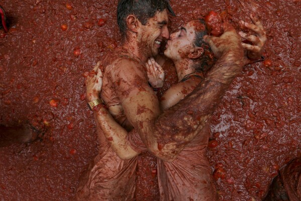 Revelers lie in a pool of squashed tomatoes during the annual "Tomatina" tomato fight fiesta, in the village of Bunol near Valencia, Spain, on Aug. 28, 2024. (AP Photo/Alberto Saiz)