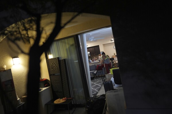 Maria, a Venezuelan immigrant who lives with her U.S. citizen husband and two daughters who have Temporary Protected Status, or TPS, vacuums a rug as the family organizes and packs for their upcoming move into a larger and nicer apartment, Saturday, April 5, 2025, in Doral, Fla. (AP Photo/Rebecca Blackwell)