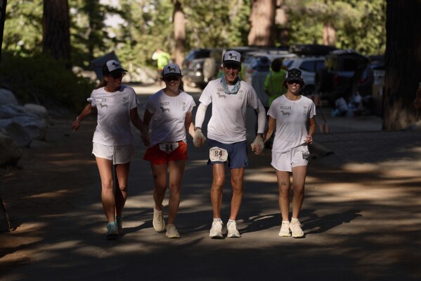 Danny Westergaard, second from right, nears the finish line of the Badwater 135 Ultramarathon beside daughters Meagan Westergaard, right, Madison Westergaard, and cousin Jennifer Drain, left, Wednesday, July 9, 2025, at Whitney Portal near Lone Pine, Calif. (AP Photo/John Locher)
