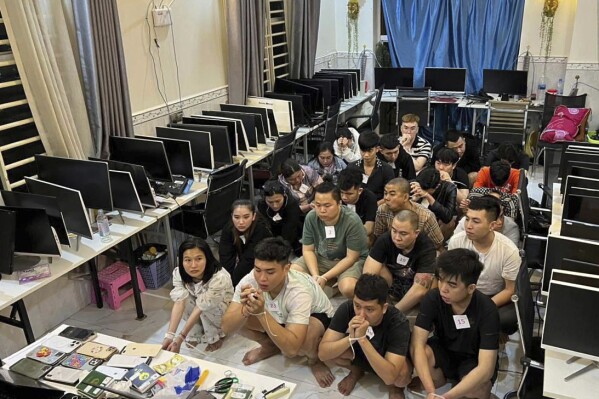 In this photo released by Agence Kampuchea Press (AKP), online scammers arrested by authorities squat in a building in Sihanoukville province, southwestern of Phnom Penh, Cambodia, Tuesday, July 15, 2025. (AKP via AP)