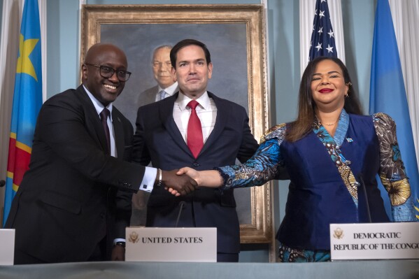 Secretary of State Marco Rubio, center, stands with Rwanda's Foreign Minister Olivier Nduhungirehe, left, and Democratic Republic of the Congo's Foreign Minister Therese Kayikwamba Wagner, right, as they shake hands after signing a peace agreement at the State Department, Friday, June 27, 2025, in Washington. (AP Photo/Mark Schiefelbein).
