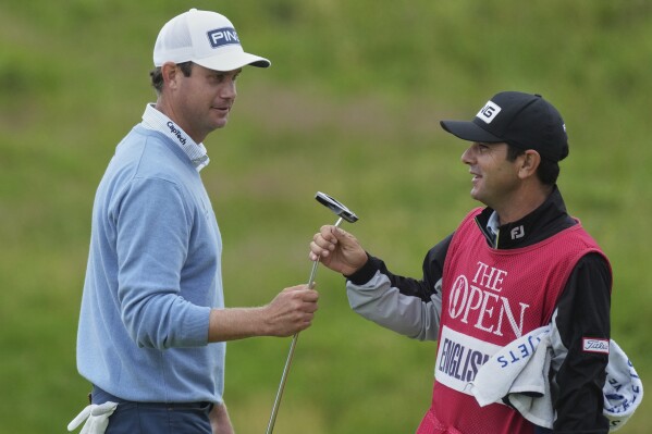 Harris English of the United States hands his club to his caddie Ramon Bescansa on the 11th green during the first round of the British Open golf championship at the Royal Portrush Golf Club, Northern Ireland, Thursday, July 17, 2025. (AP Photo/Jon Super)
