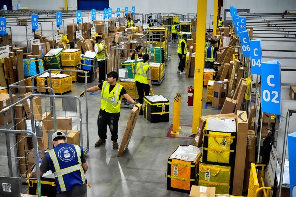 Amazon employees load packages on carts before being put on to trucks for distribution for Amazon's annual Prime Day event at an Amazon's DAX7 delivery station, July 16, 2024, in South Gate, Calif. (AP Photo/Richard Vogel, File)