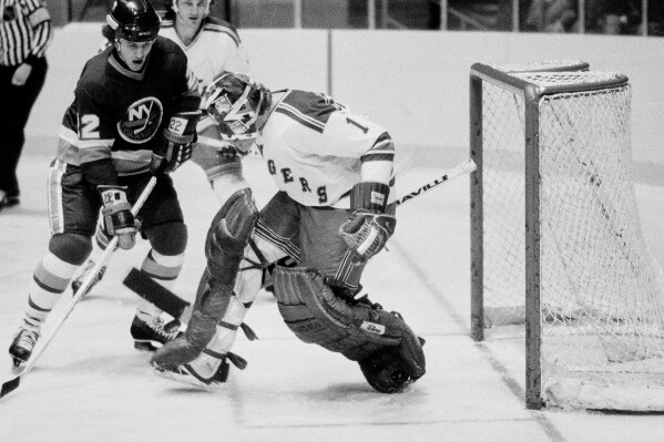 New York Islanders' Mike Bossy, left, watches the puck about to be deflected by New York Rangers goalie Wayne Thomas during an NHL hockey game at New York's Madison Square Garden, Nov. 12, 1978. (AP Photo/Ray Stubblebine, File)