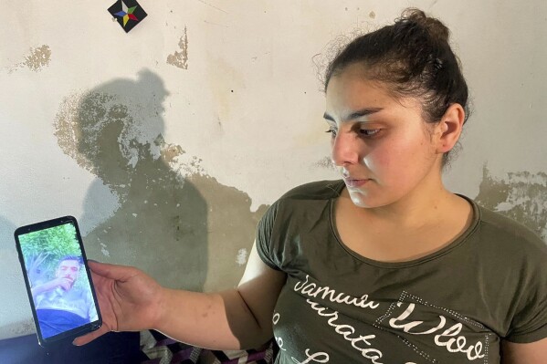Druze woman, Evelyn Azzam, 20, shows a picture of her husband who was wounded in clashes between Syrian government forces and Druze militias in Sweida, during an interview with The Associated Press in the southern Damascus suburb of Jaramana, Wednesday, July 16, 2025. (AP Photo/Abdulrahman Shaheen)