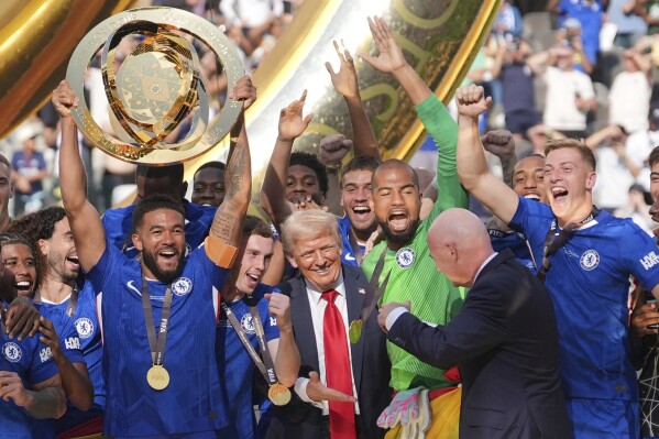 President Donald Trump reaches out to shake hands with FIFA President Gianni Infantino as Chelsea's Reece James (24) lifts the trophy following the Club World Cup final soccer match between Chelsea and PSG in East Rutherford, N.J., Sunday, July 13, 2025. (AP Photo/Seth Wenig)
