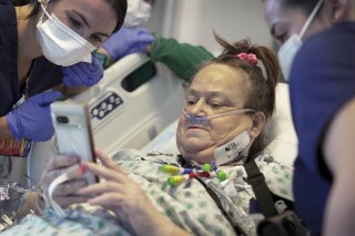 FILE - Lisa Pisano looks at photos of her dog after her surgeries at NYU Langone Health in New York on Monday, April 22, 2024. Pisano, who received a pig kidney transplant -- along with an implanted device to keep her heart beating – has died, her surgeon announced Tuesday, July 9, 2024. She was near death from dual kidney and heart failure when surgeons at NYU Langone Health performed the dramatic pair of surgeries. (AP Photo/Shelby Lum, File)