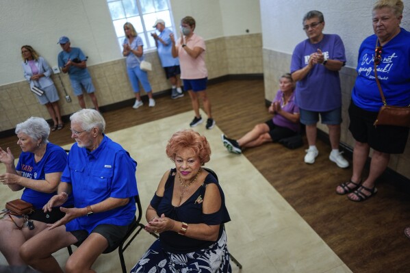 Merle Barefoot, center, who moved to The Villages 31 years ago from Georgia, wears an American flag pin during a meeting of The Villages Democrats Club at Wildwood Community Center in Wildwood, Fla., Saturday, Sept. 14, 2024. (AP Photo/Rebecca Blackwell)