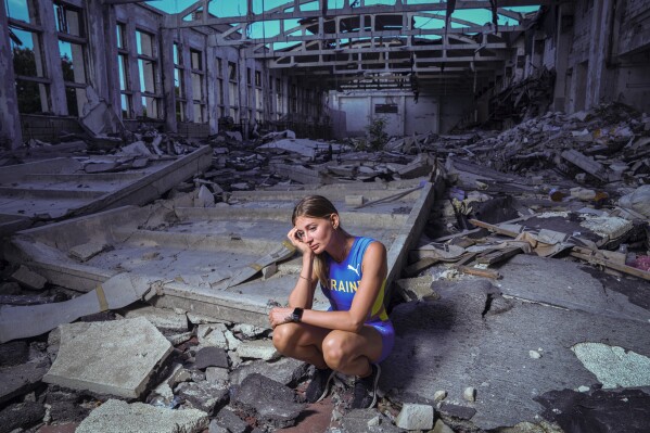 Kateryna Tabashnyk, a high jumper, sits for a portrait Sunday, June 9, 2024, at the athletics arena of the "Polytechnic" sports complex, which was destroyed by a Russian rocket attack, in Kharkiv, Ukraine. (AP Photo/Evgeniy Maloletka)