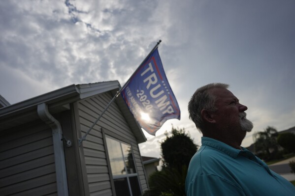 A Trump flag flies from the home of Dave Farraday, a 74-year-old retired utility worker from Pennsylvania, in The Villages, Fla., Sunday, Sept. 15, 2024. Farraday, who registered to vote for the first time in 2016 to support Donald Trump, will again vote for the former President and Republican presidential nominee, over economic issues, but says he would have preferred different candidates to run. Two homes on his street have lawn signs supporting Harris, but Farraday says political differences don't get in the way of neighborliness. "We're all here for one reason, we're retired," he said. "We're relaxing…trying to." (AP Photo/Rebecca Blackwell)