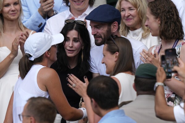 Courteney Cox, center, and Johnny McDaid celebrate with Poland’s Iga Swiatek as she greets her coaches, friends and family after beating Amanda Anisimova of the U.S. to win the women’s singles final at the Wimbledon Tennis Championships in London, Saturday, July 12, 2025.(Andrew Matthews, PA via AP)