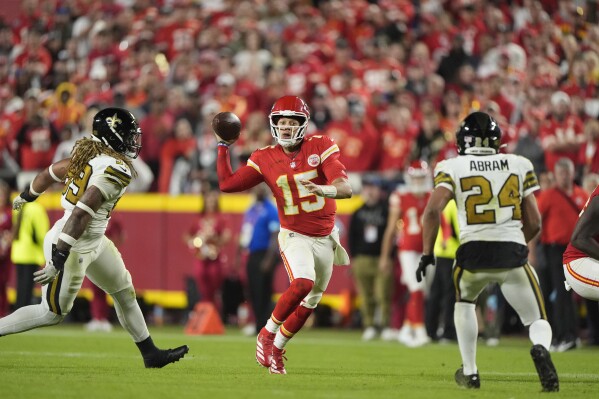 Kansas City Chiefs quarterback Patrick Mahomes, center, runs with the ball as New Orleans Saints defensive end Chase Young and safety Johnathan Abram (24) defend during the second half of an NFL football game Monday, Oct. 7, 2024, in Kansas City, Mo. (AP Photo/Charlie Riedel)