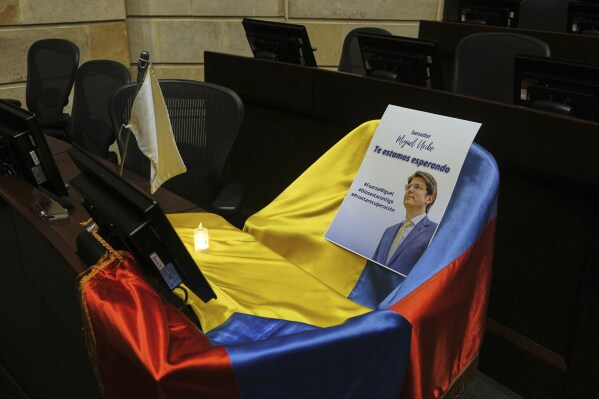 Un folleto muestra la imagen del senador colombiano Miguel Uribe Turbay sobre una bandera colombiana que cubre su escaño en el Congreso, en Bogotá, Colombia, el 9 de junio de 2025. (AP Foto/Iván Valencia, Archivo)