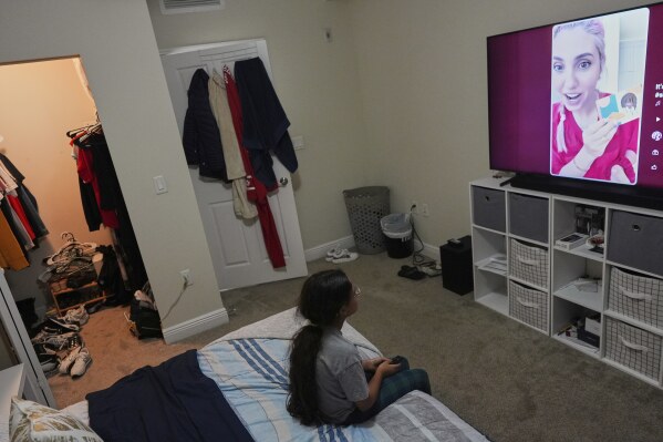 A 9-year-old girl with Temporary Protected Status, or TPS, who was born in Venezuela, but who fluently speaks only English and is in the gifted program at her school, watches TV in her family's apartment, Saturday, April 5, 2025, in Doral, Fla. (AP Photo/Rebecca Blackwell)