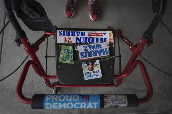 Stickers for the Democratic party adorn the walker of Shelly Newman, 73, as she leaves a meeting of The Villages Democratic Club, at Wildwood Community Center in Wildwood, Fla., Saturday, Sept. 14, 2024. Newman says people see her stickers and approach her, whispering "You're a Democrat too?" Newman tells them, "Don't whisper. Democrats can be loud and proud too." (AP Photo/Rebecca Blackwell)