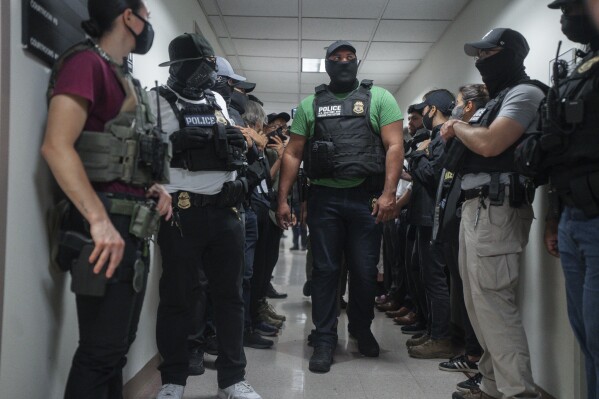 Masked federal agents wait outside an immigration courtroom, July 8, 2025, in New York. (AP Photo/Olga Fedorova, File)