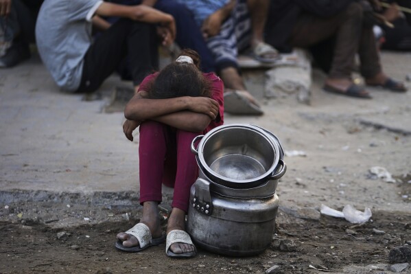 Palestinians wait for donated food at a community kitchen in Gaza City, in the northern Gaza Strip, Monday, July 14, 2025. (AP Photo/Jehad Alshrafi)