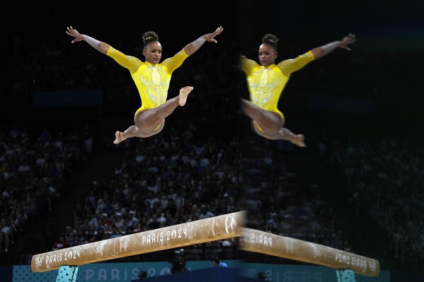 Rebeca Andrade, of Brazil, is reflected on a surface as she performs on the balance beam during the women's artistic gymnastics all-around finals in Bercy Arena at the 2024 Summer Olympics, Thursday, Aug. 1, 2024, in Paris, France. (AP Photo/Charlie Riedel)