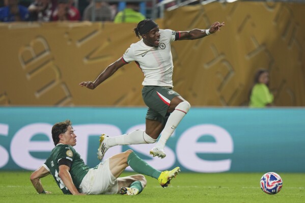 Chelsea's Noni Madueke, right, jumps over Palmeiras' Agustin Giay, left, during the Club World Cup quarterfinal soccer match between Palmeiras and Chelsea in Philadelphia, Friday, July 4, 2025. (AP Photo/Chris Szagola)