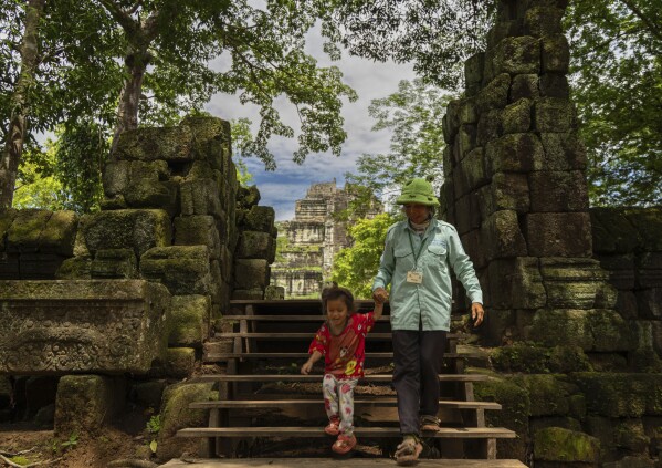 A woman holds the hand of her granddaughter and exits Koh Ker Temple, a UNESCO World Heritage site in Preah Vihear, Cambodia, still undergoing humanitarian demining efforts as of Monday, June 9, 2025. (AP Photo/Anton L. Delgado)