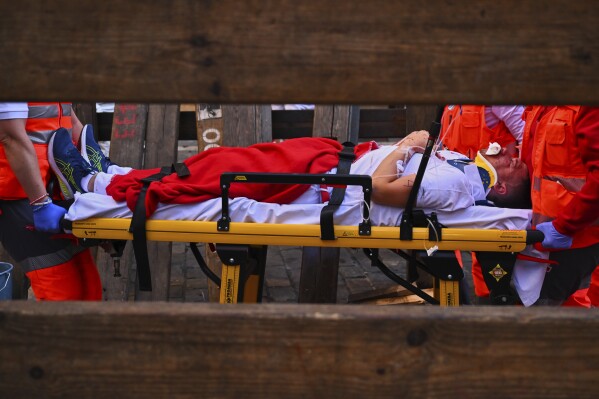 A runner who was injured during the running of the bulls is carried on a stretcher by a medical team at the San Fermín Festival in Pamplona, Spain, Thursday, July 10, 2025. (AP Photo/Miguel Oses)