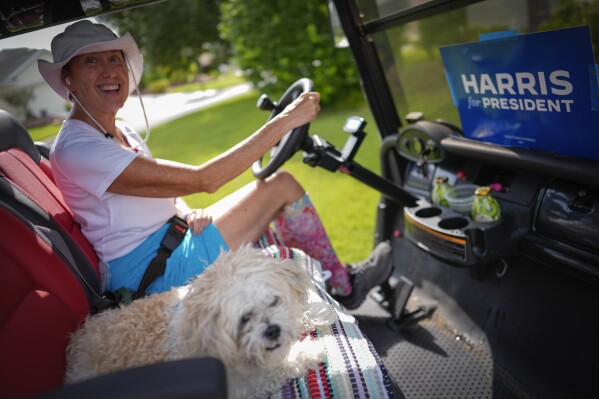 A retired government worker who preferred not to give her name drives a golf cart decorated with a "Harris for President" sign in The Villages, Fla., Sunday, Sept. 15, 2024. (AP Photo/Rebecca Blackwell)