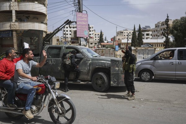 Syrian citizens salute members of Syria's security forces deployed in the town of Sahnaya, south of Damascus, Syria, Thursday, May 1, 2025, a day after clashes erupted between members of the minority Druze sect and pro-government fighters which left several people dead. (AP Photo/Ghaith Alsayed)