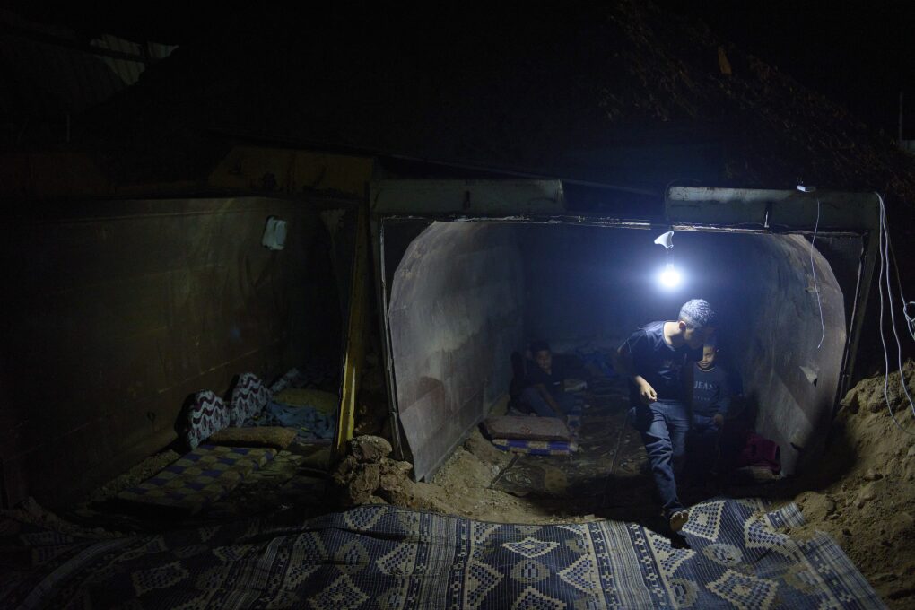 The Gaboa family, Bedouins living in Al-Furaa village in southern Israel, gather around the makeshift bomb shelter they made from two gravel trucks buried in dirt to protect them from incoming Iranian fire, Tuesday, June 17, 2025. (AP Photo/Maya Alleruzzo)
