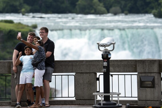 Tourists pose for selfies in Niagara Falls, Ontario on July 16, 2021. (Peter Power/The Canadian Press via AP, File)