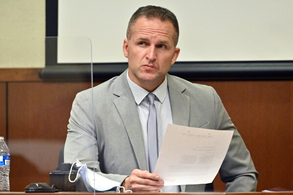 Former Louisville Police officer Brett Hankison examines a document as he answers questions from the prosecution, March 2, 2022, in Louisville, Ky. (AP Photo/Timothy D. Easley, Pool, File)