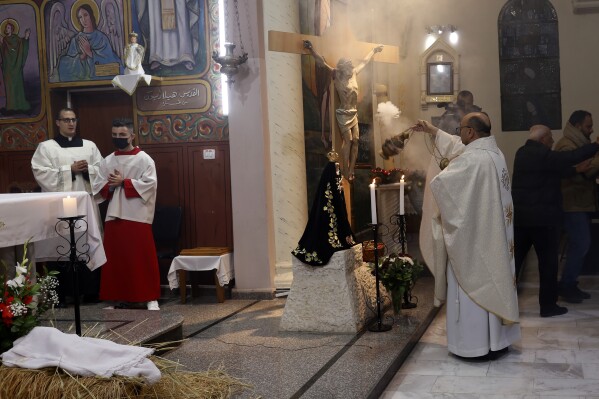 FILE -Fr. Gabriel Romanelli, Latin parish priest of Gaza Strip, left, prays during the midnight Christmas Eve mass at Deir Al Latin Holy Family Catholic Church in Gaza City, Dec. 24, 2021. (AP Photo/Adel Hana, File)
