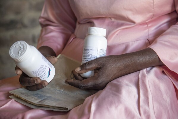 Florence Makumene holds HIV medication that she received through funding from the U.S. President's Emergency Plan for AIDS Relief (PEPFAR), along with her hospital records book, at her home in Harare, Zimbabwe, Feb. 7, 2025. (AP Photo/Aaron Ufumeli, File)