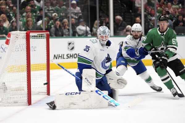 Vancouver Canucks goaltender Thatcher Demko (35) watches a shot go wide of the net as Conor Garland (8) helps against pressure from Dallas Stars right wing Evgenii Dadonov (63) in the first period of an NHL hockey game in Dallas, April 8, 2025. (AP Photo/LM Otero, File)