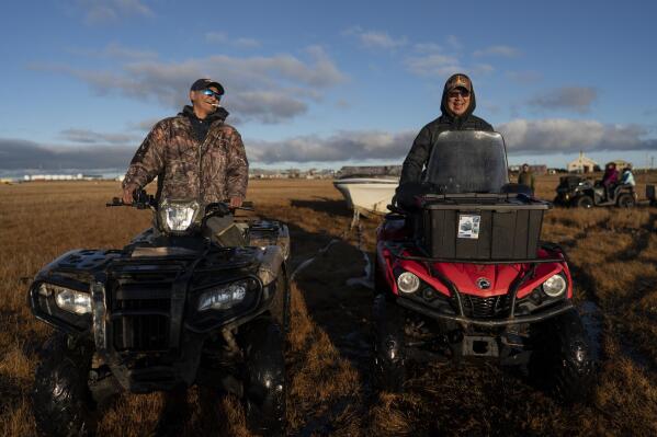 Sitting on their ATVs, seal hunters John Kokeok, right, and Ralph Olanna share a light moment before pulling a boat into the water in Shishmaref, Alaska, Saturday, Oct. 1, 2022. Kokeok's brother Norman, a skilled hunter, knew the ice and trails well. Yet during a hunting trip in 2007, his snowmobile fell through ice that melted earlier than usual, and he was killed. John blames climate change and he has been retelling his story ever since in hopes of warning younger generations and finding solutions to protect his island community. Like others, he voted to relocate Shishmaref to safer ground. But he also wants to protect its traditions, its way of life. The only way he'd leave now is if he'd had to evacuate. (AP Photo/Jae C. Hong)