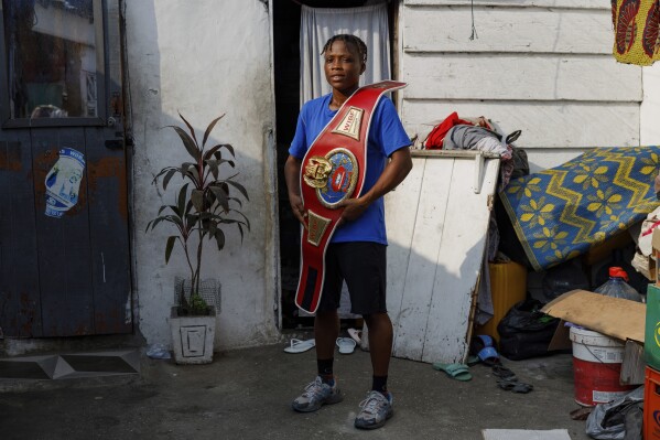 Ghana's first-ever female world boxing champion, Abigail Kwartekaa Quartey, poses for a photo with her world title belt at her house in the Jamestown district in Accra, Ghana, Wednesday, Jan. 22, 2025. (AP Photo/Misper Apawu)