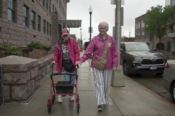 Jacque Farnham, 60, left, walks with her mother, Janith, 80, to the Visual Arts Center at the Washington Pavilion in Sioux Falls, S.D., on May 20, 2025. (AP Photo/Shelby Lum)