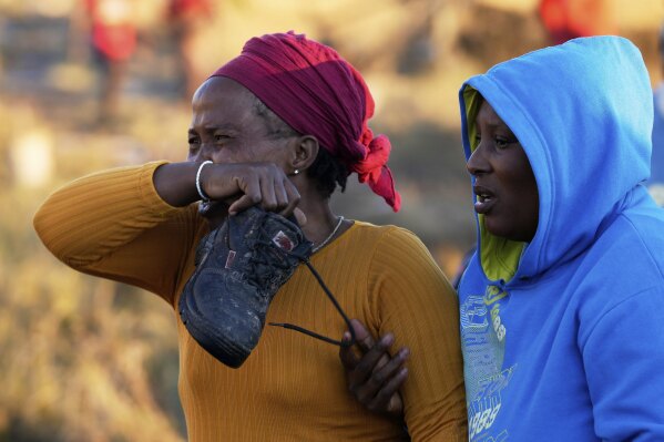 A relative reacts as bodies of her sister and three daughters were retrieved from inside a one room house, after floods swept through the area in Mthatha, South Africa, Thursday, June 12, 2025. (AP Photo/Themba Hadebe)