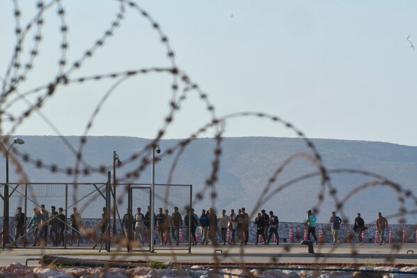 Migrants rescued south of Crete walk after their arrival at the the port of Lavrio, Greece, on Thursday, July 10, 2025. (AP Photo/Petros Giannakouris)