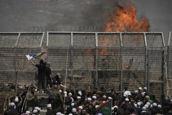 Druze from Syria and Israel protest on the Israeli-Syrian border, in Majdal Shams in the Israeli-controlled Golan Heights, Wednesday, July 16, 2025, amid the ongoing clashes between Syrian government forces and Druze armed groups in the southern Syrian city of Sweida. (AP Photo/Leo Correa)