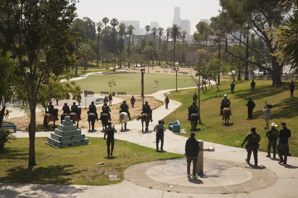 Federal agents ride on horseback at MacArthur Park, Monday, July 7, 2025, in Los Angeles. Their uniforms read "Police U.S. Border Patrol," and "HSI," which stands for Homeland Security Investigations. (AP Photo/Damian Dovarganes)
